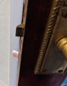 A little finger reaches around the edge of the door.